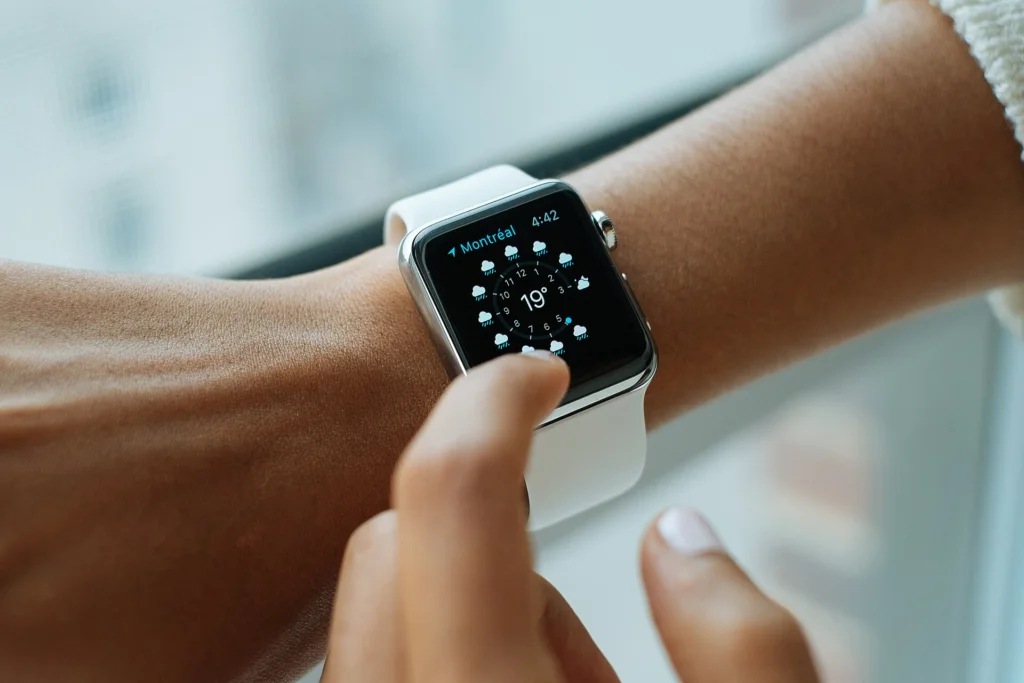 Eine Person tippt auf eine Apple Watch mit weißem Armband am Handgelenk